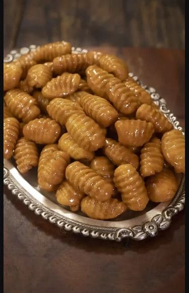 Bellam Gavalu — shell-shaped Andhra fried sweets coated in dark jaggery, piled in bowl