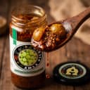 Amla Pickle — close-up of spiced oil and pickle pieces on wooden spoon