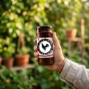 Hand holding Andhra Store Chicken Pickle jar outdoors — authentic homemade pickle
