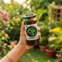 Hand holding Andhra Store Curry Leaves Pickle jar outdoors — authentic homemade pickle
