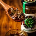 Curry Leaves Pickle — close-up of spiced oil and pickle pieces on wooden spoon