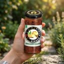 Hand holding Andhra Store Ginger Pickle jar outdoors — authentic homemade pickle