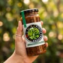 Hand holding Andhra Store Gongura Pickle jar outdoors — authentic homemade pickle
