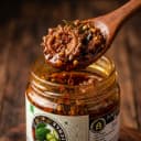Karela Pickle — close-up of spiced oil and pickle pieces on wooden spoon