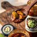 Mango Pickle — close-up of spiced oil and pickle pieces on wooden spoon