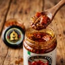 Tomato Pickle — close-up of spiced oil and pickle pieces on wooden spoon